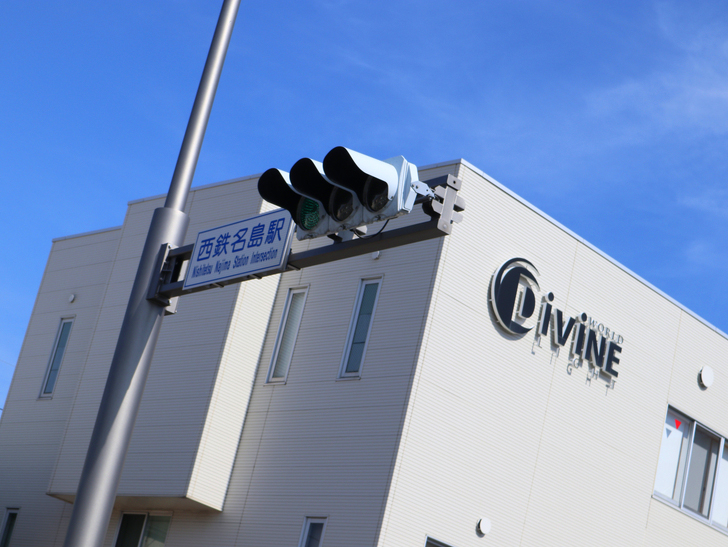 【福岡市東区】晴れた青空が似合う「名島駅」の周辺写真：「西鉄名島駅」交差点と「Divine」のロゴ